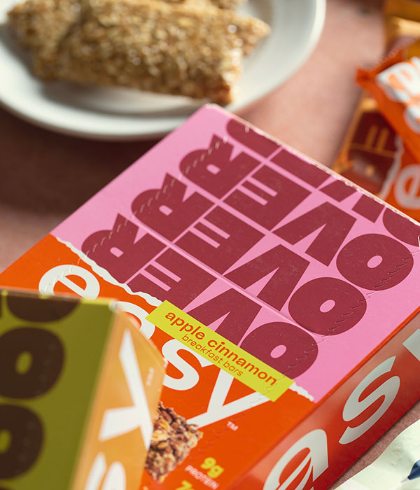A Box of Over Easy Breakfast Bars with a Plate of Breakfast Bars in the Background