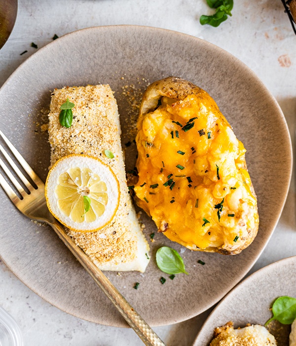 Air fryer crusted halibut served on a plate with a lemon slice and a Heinen's Daily Bites Twice Baked Potato