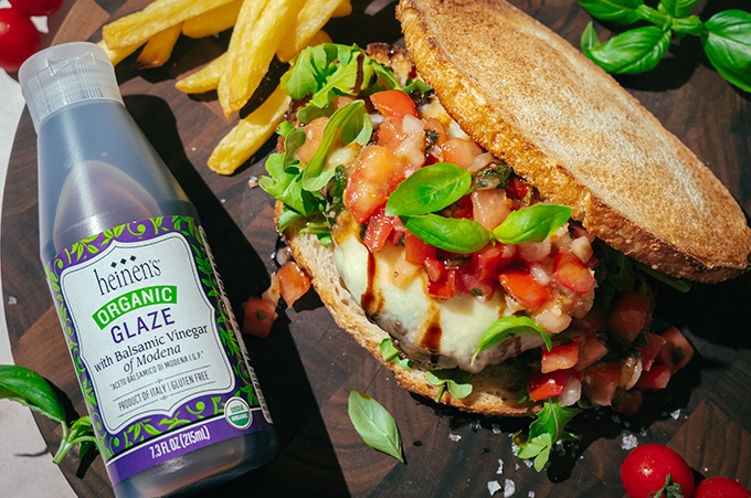 Bruschetta burger placed beside a bottle of Heinen's Balsamic Glaze 