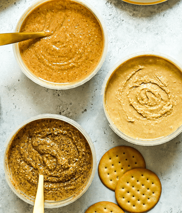 Three Open Containers of Heinen's Nut Butter with Spoons