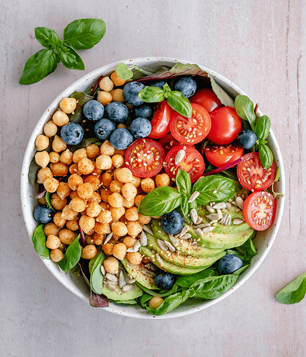 A Fresh Green Salad in a Bowl with Chickpeas, Tomatoes, Blueberries, Avocados and Seeds