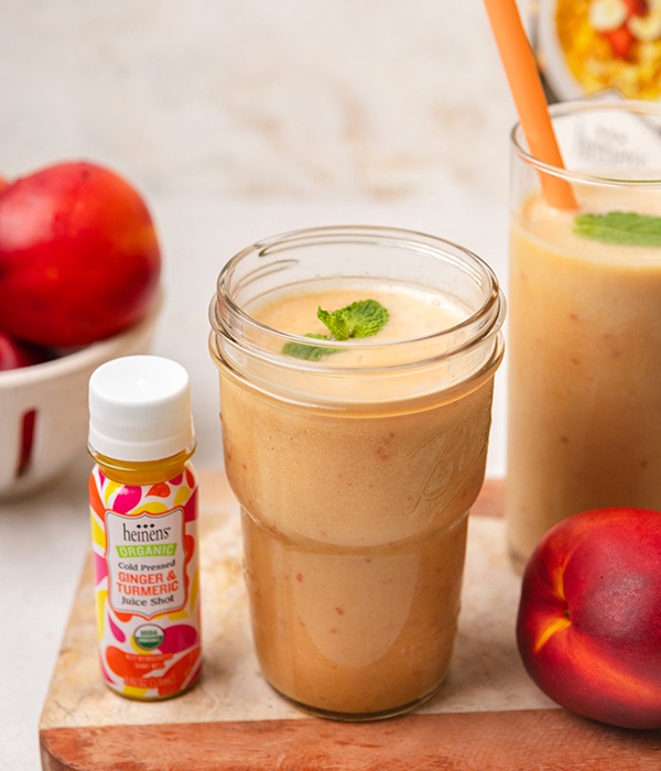 Ginger Turmeric Smoothie in glass beside a Ginger and Turmeric Heinen's Juice Shot