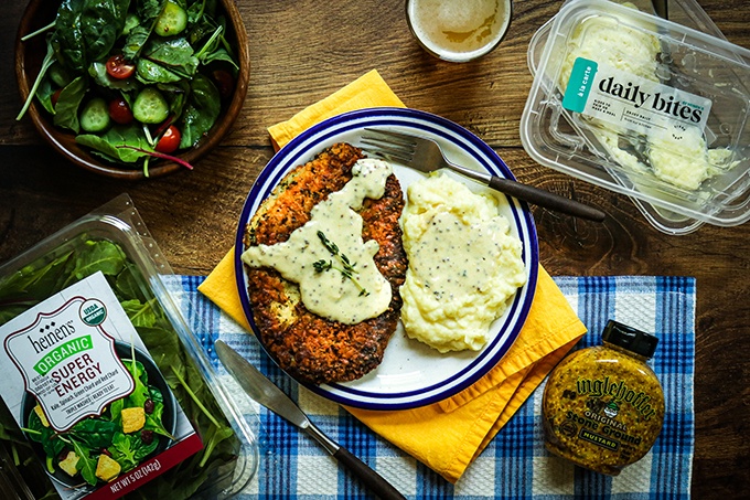 Pork Schnitzel with Creamy Mustard Sauce on a plate with a side of mashed potatoes and a salad tossed in a simple mustard vinaigrette (made with Heinen's super energy power salad blend)