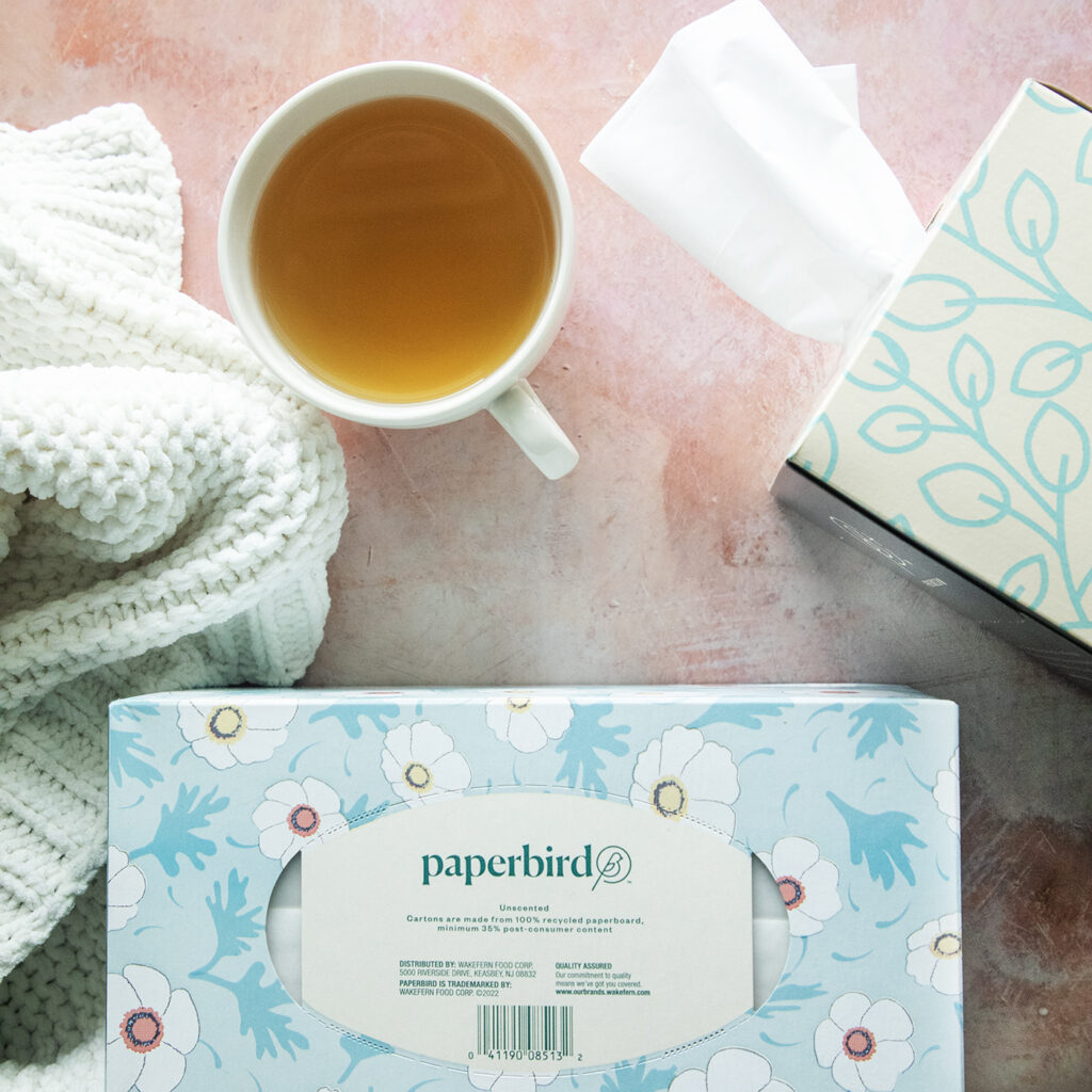 Two Boxes of Paperbird Tissues Beside a Cup of Tea