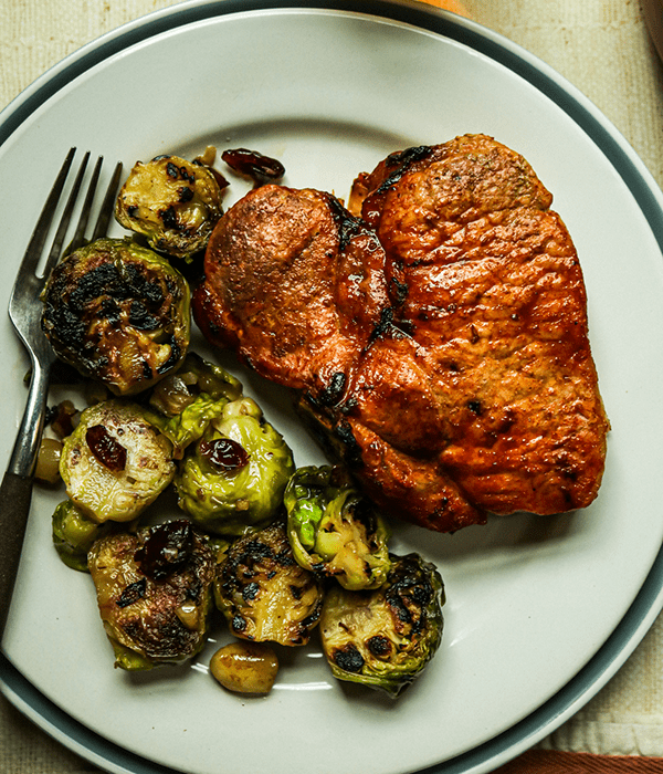 Heinen's Maple Brined Bone-In Pork Chop on a Plate with Heinen's Brussels Sprouts with Hazelnuts and Cranberries