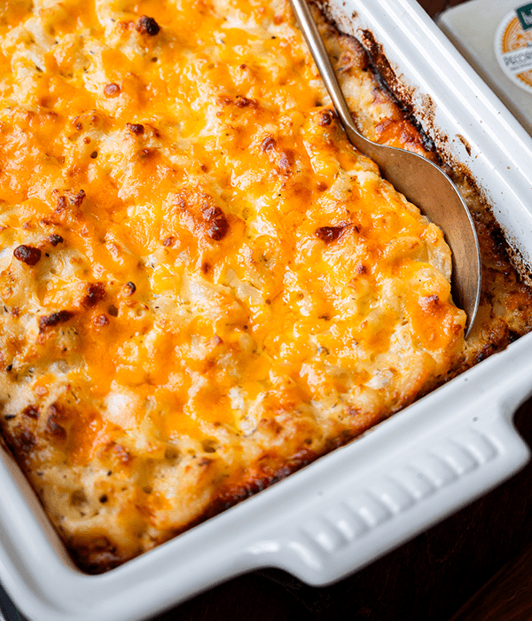 A Close Up Image of Five Cheese Baked Macaroni and Cheese with a Metal Serving Spoon