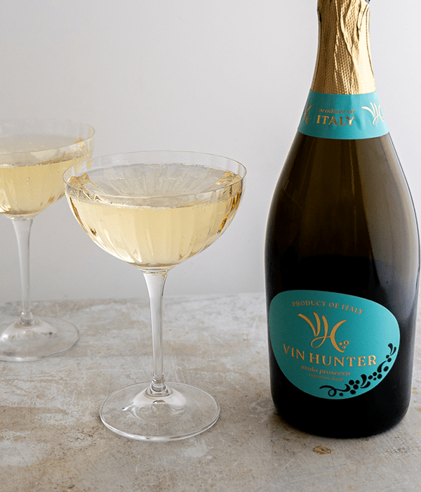 A Bottle of Vin Hunter Prosecco Beside Two Filled Champagne Coupes