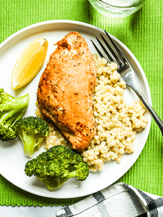 Marinated chicken, couscous, and broccoli on a plate.