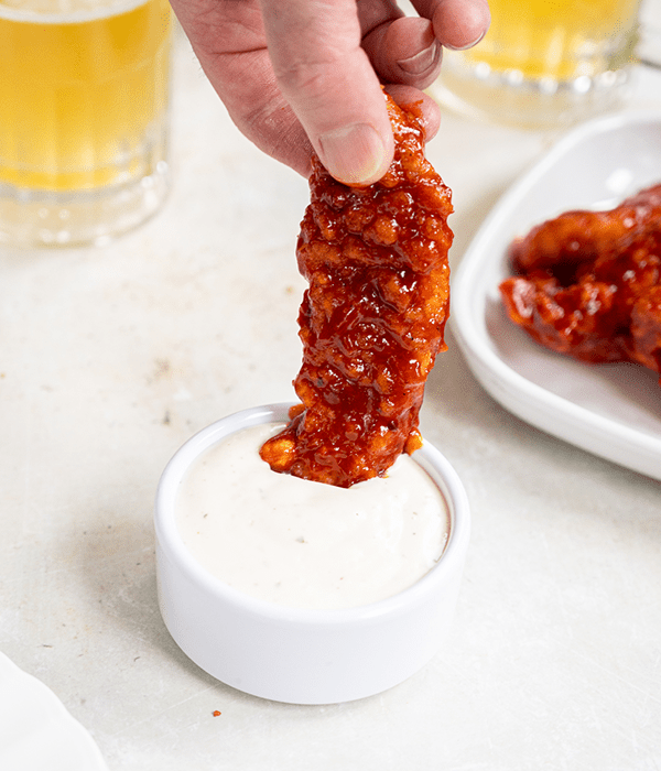 A Honey Chipotle Chicken Tender Being Dipped in a Bowl of Ranch Dressing