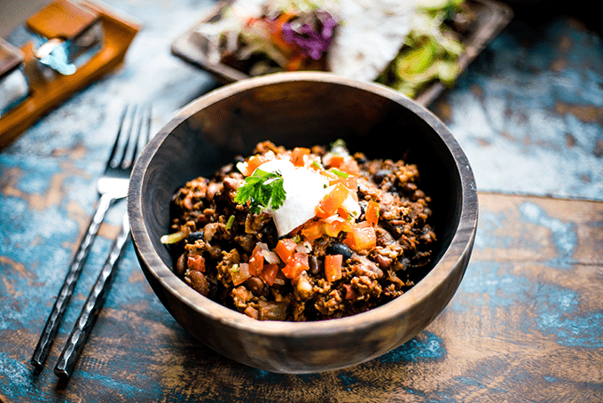 Bowl with taco meat, beans, tomatoes, and sour cream.
