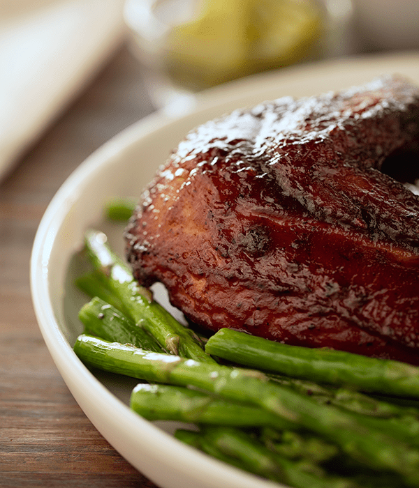 Honey BBQ Smoked Chicken Thigh in a Serving Bowl with Cooked Asparagus