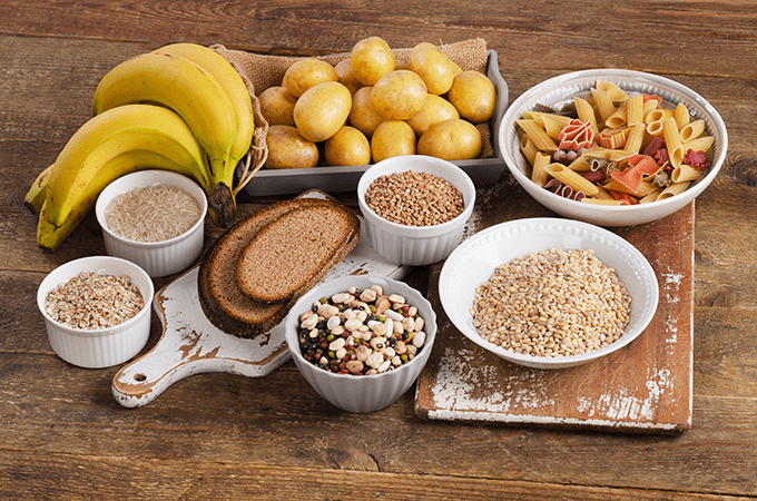 An assortment of carbohydrate full foods including breads, grains, pastas, potatoes, and bananas