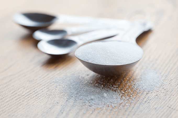 Measuring spoons on a counter with one filled with sugar.