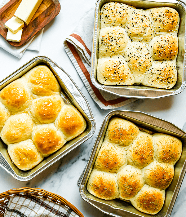 Three Pans filled with Fresh Baked Honey Butter Dinner Rolls, Garlic and Herb Dinner Rolls, and Everything Bagel Dinner Rolls
