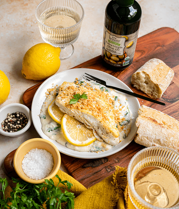 Easy Halibut Florentine on a Plate Surrounded by Fresh Bread, Herbs, Spices, and Olive Oil