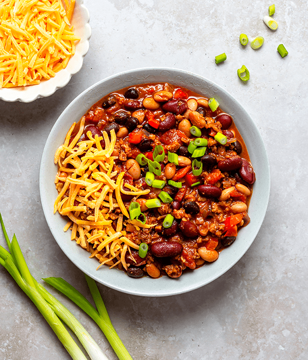 A Big Bowl of Superfood Chili with Green Onions and Shredded Cheese
